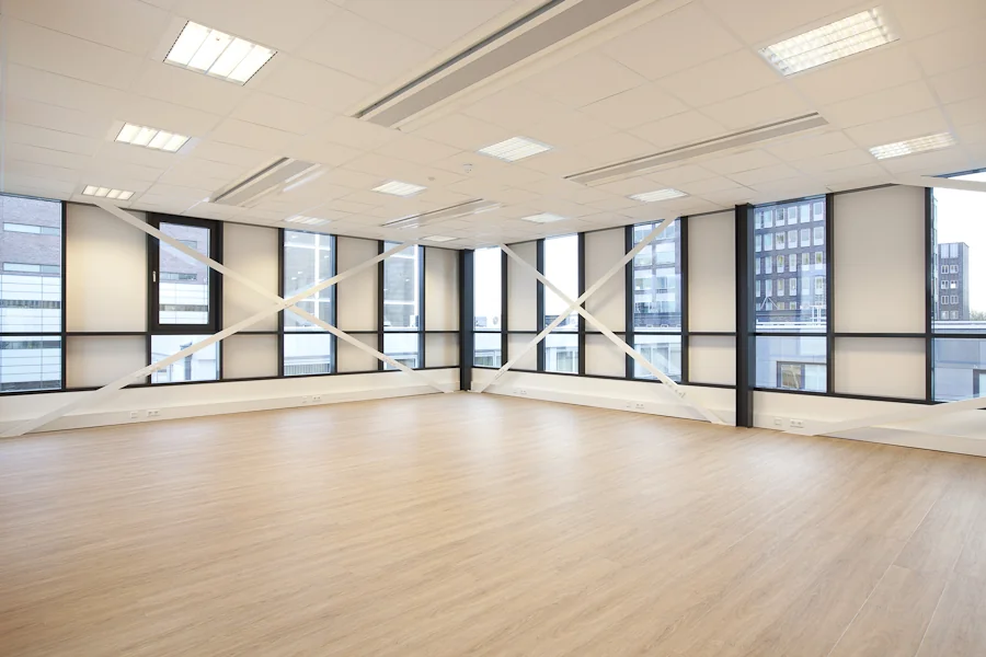 Licht, leeg kantoor met grote ramen aan de De Boelelaan en een houten vloer.